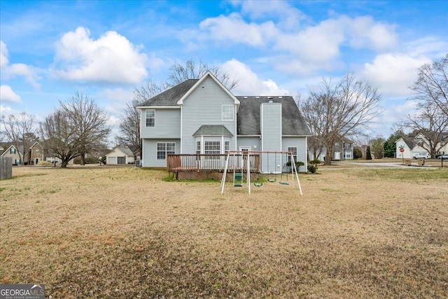 rear view of property with a playground, a yard, and a deck