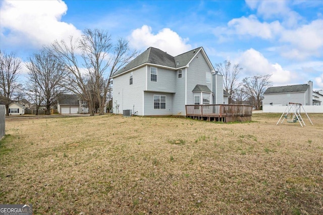 rear view of property featuring a playground, a deck, central air condition unit, and a lawn