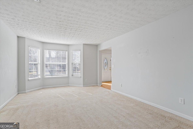 spare room with light carpet and a textured ceiling