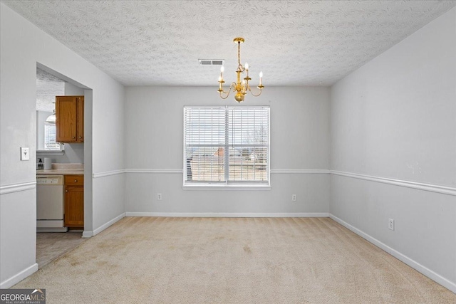 carpeted spare room featuring a textured ceiling and a chandelier