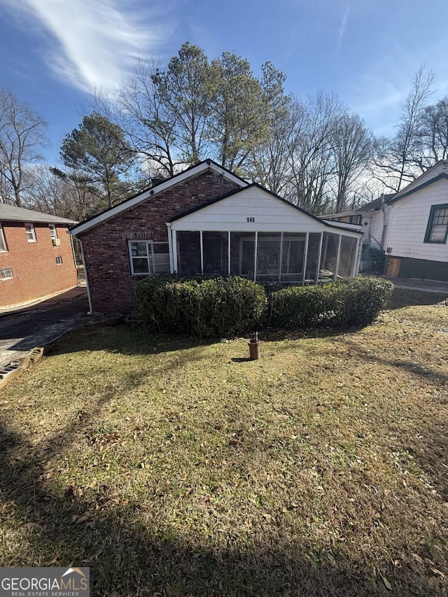 back of property featuring a sunroom and a yard