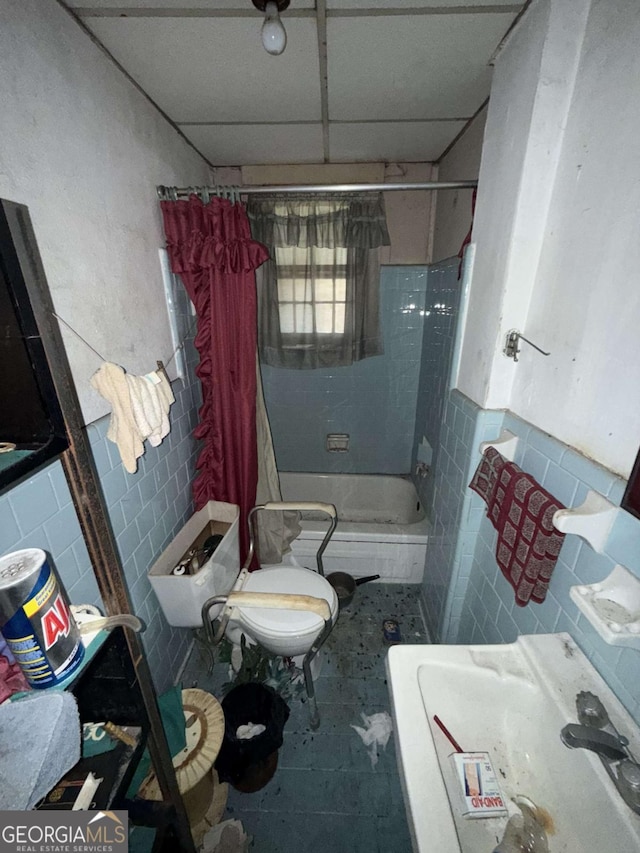 bathroom with toilet, tile patterned flooring, and tile walls