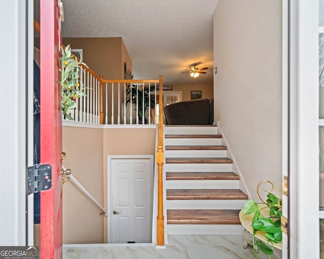 stairs featuring ceiling fan