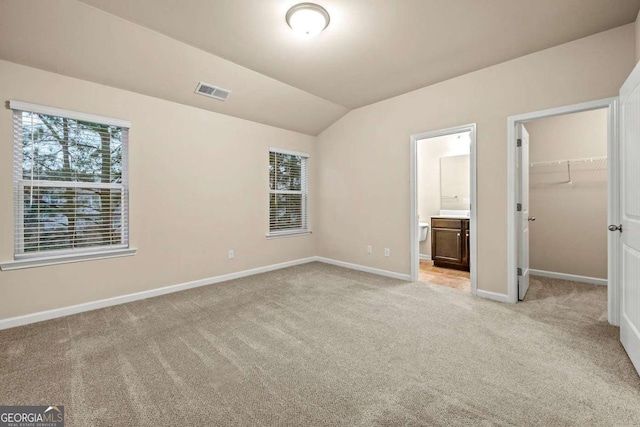6040 Oakley Rd, Union City, GA 30291 - unfurnished bedroom with vaulted ceiling, a spacious closet, light colored carpet, and ensuite bath