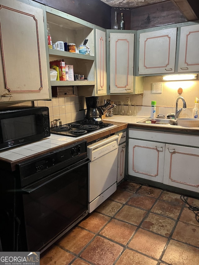 kitchen with white cabinetry, sink, tile counters, and black appliances