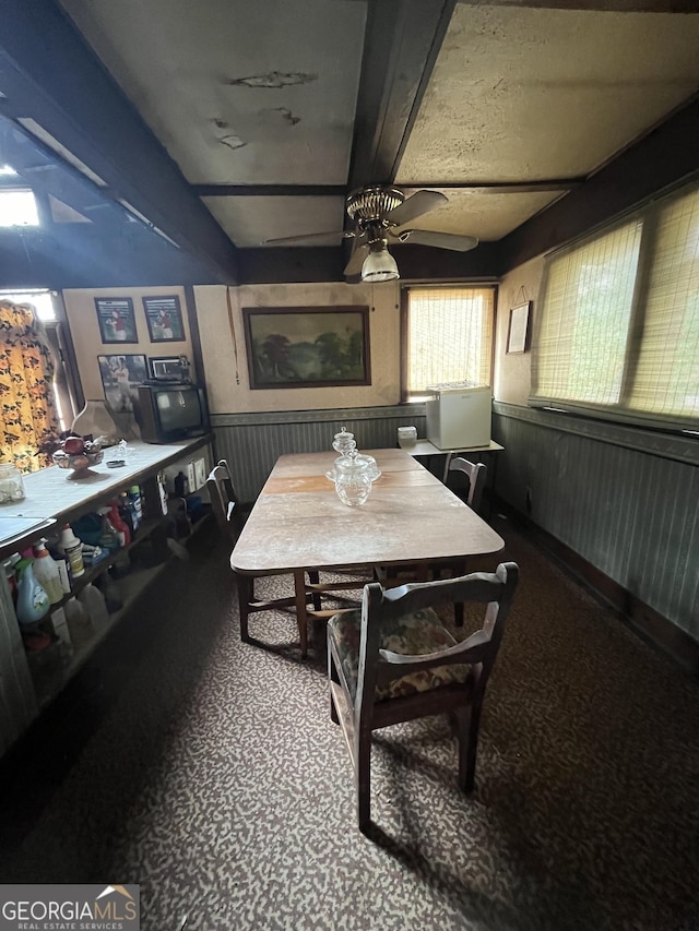 dining room with beamed ceiling, ceiling fan, and carpet