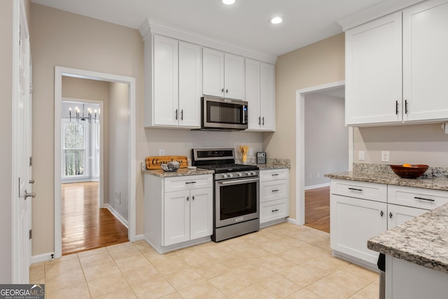 kitchen with white cabinetry, light stone counters, and stainless steel appliances