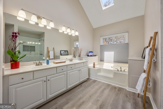 bathroom with vanity, vaulted ceiling with skylight, hardwood / wood-style floors, and shower with separate bathtub