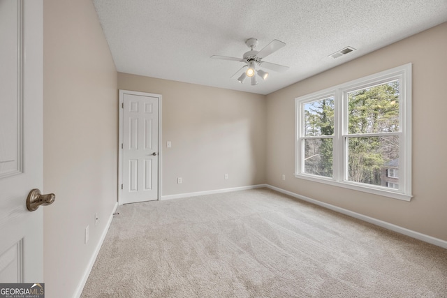 spare room with ceiling fan, light colored carpet, and a textured ceiling