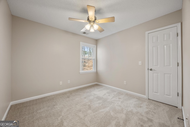 carpeted spare room with ceiling fan and a textured ceiling