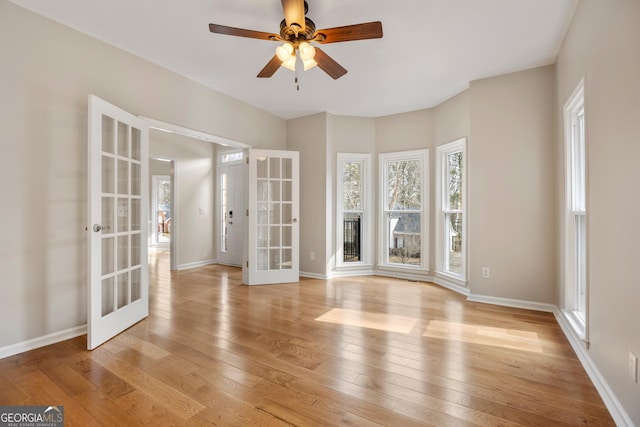 empty room with french doors, ceiling fan, and light hardwood / wood-style floors