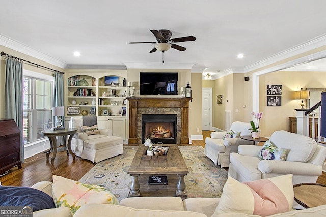 living room with hardwood / wood-style floors, a fireplace, ornamental molding, and ceiling fan