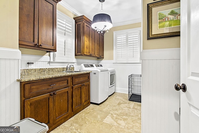 washroom with cabinets, crown molding, washer and dryer, and sink