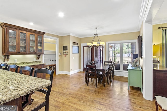 dining area featuring ornamental molding, light hardwood / wood-style floors, and a notable chandelier