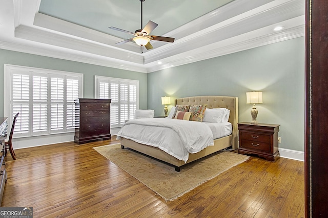 bedroom with crown molding, a tray ceiling, and hardwood / wood-style floors