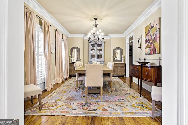 dining area with ornamental molding, wood-type flooring, and a notable chandelier