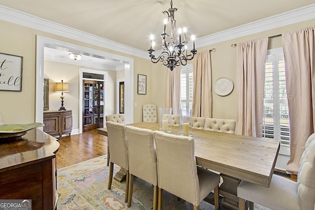 dining area featuring crown molding, an inviting chandelier, and hardwood / wood-style floors