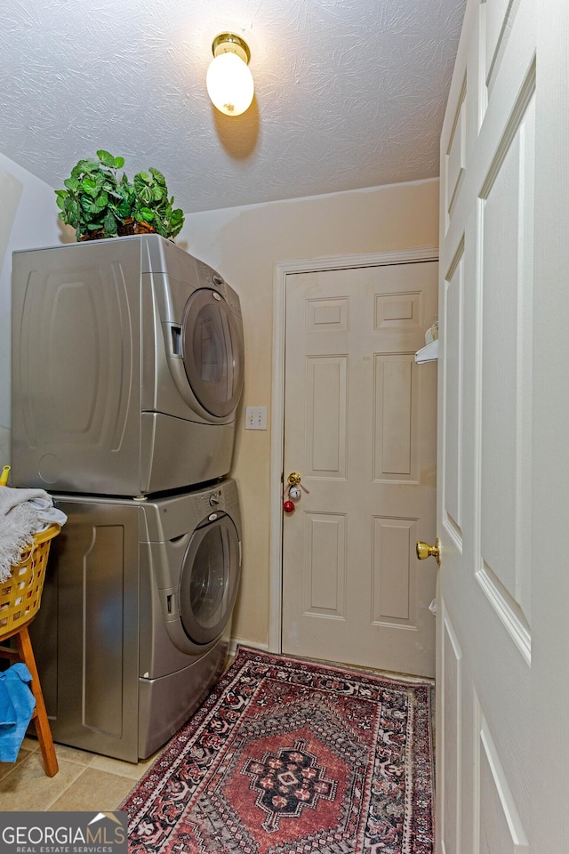 washroom featuring stacked washer / drying machine, light tile patterned floors, and a textured ceiling