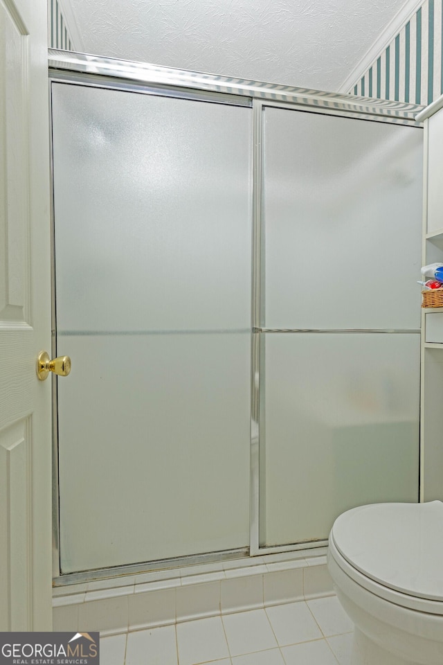 bathroom with toilet, a shower with shower door, and tile patterned flooring