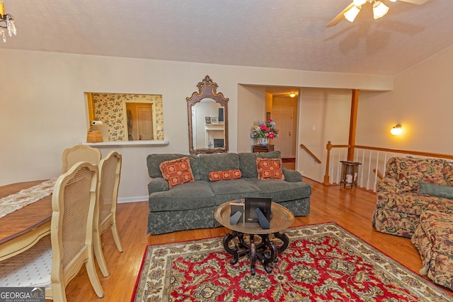 living room with ceiling fan, a textured ceiling, and light hardwood / wood-style flooring