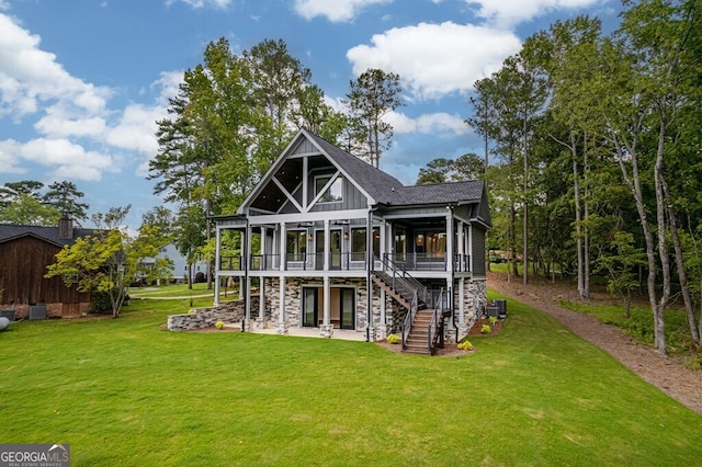 rear view of property featuring a wooden deck, a patio, and a lawn