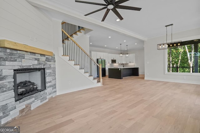 unfurnished living room with crown molding, a fireplace, sink, and light wood-type flooring