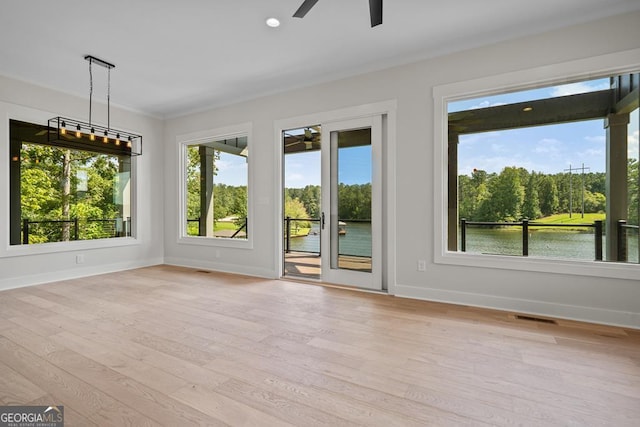 interior space with ceiling fan, light hardwood / wood-style flooring, plenty of natural light, and a water view