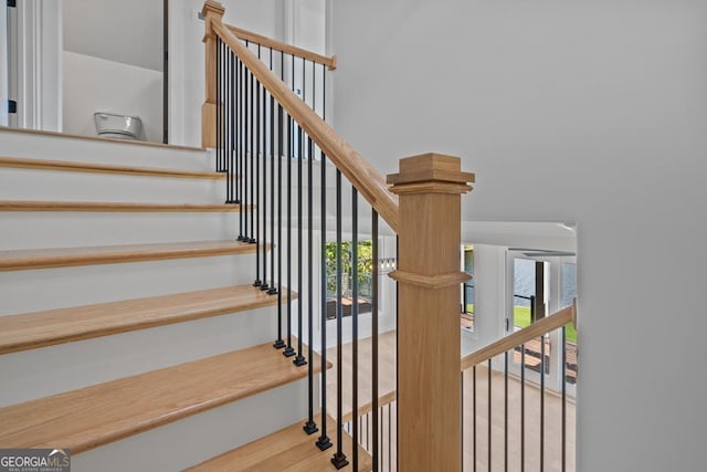 staircase featuring a towering ceiling and wood-type flooring