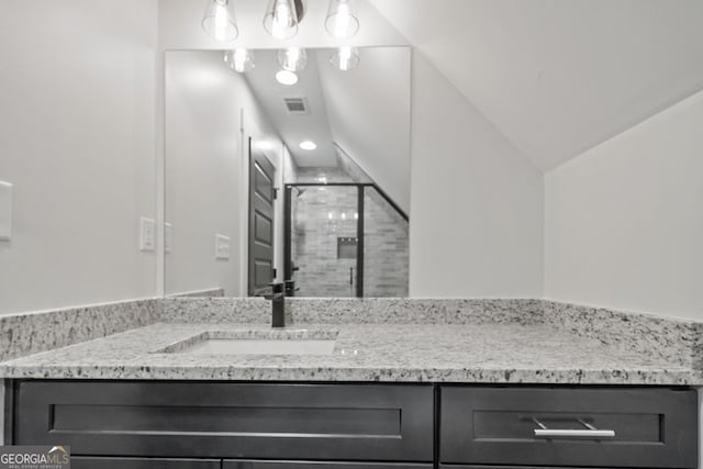 bathroom featuring an enclosed shower, vanity, and vaulted ceiling