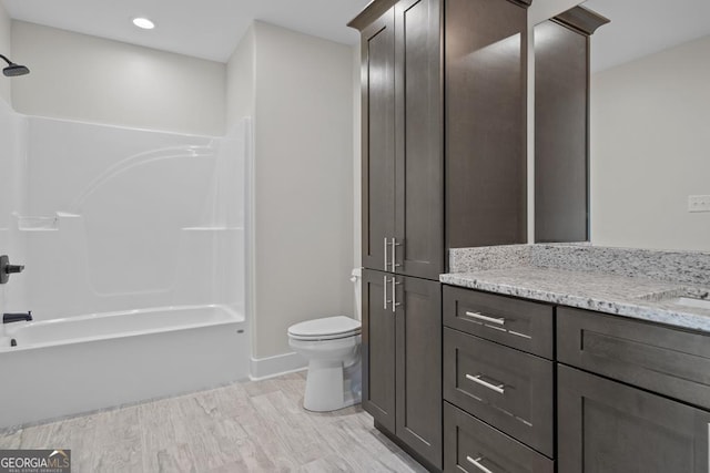 full bathroom with vanity, hardwood / wood-style flooring, shower / tub combination, and toilet