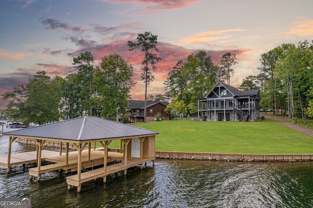 view of dock with a water view and a lawn