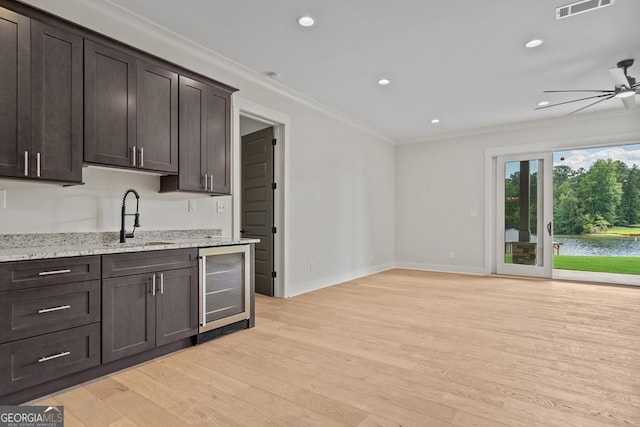 kitchen featuring dark brown cabinetry, sink, wine cooler, and light stone countertops