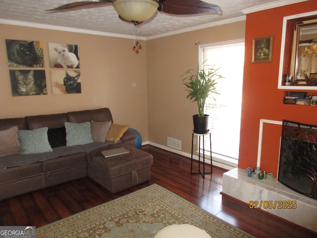 living room featuring crown molding, hardwood / wood-style floors, a fireplace, and ceiling fan