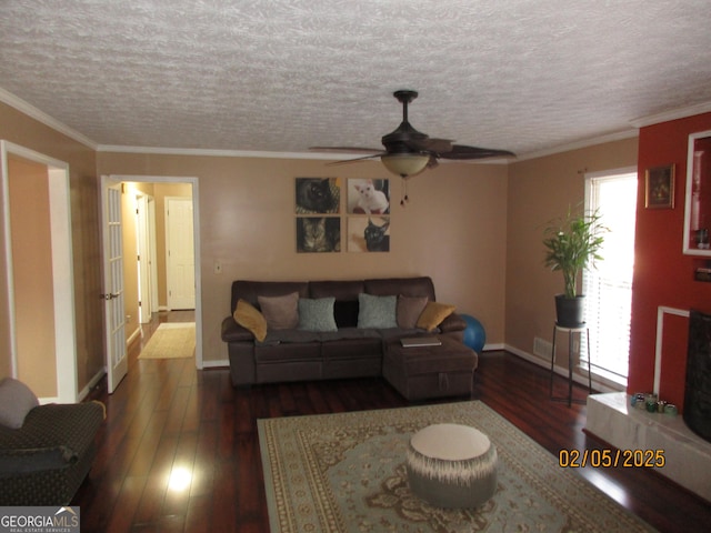 living room featuring crown molding, dark wood-type flooring, ceiling fan, and a textured ceiling