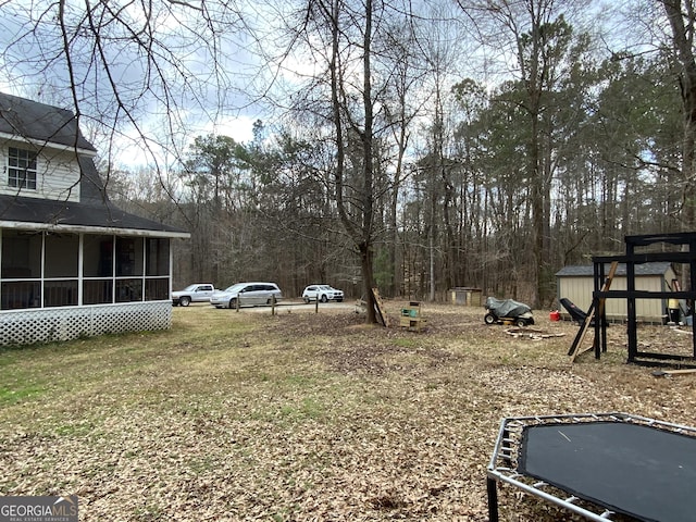 view of yard featuring a trampoline and a sunroom