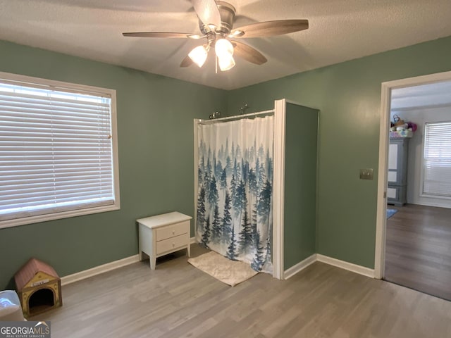 interior space with ceiling fan, wood-type flooring, and a textured ceiling