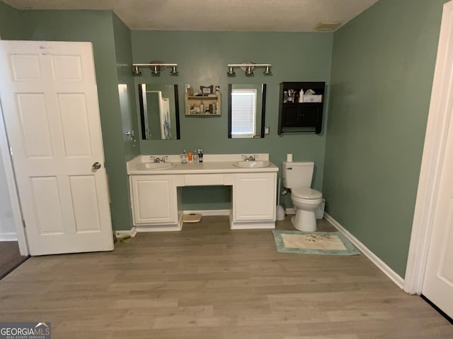 bathroom featuring vanity, toilet, wood-type flooring, and a textured ceiling