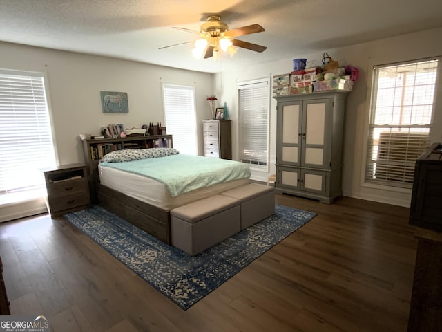 bedroom with ceiling fan, dark wood-type flooring, and a textured ceiling