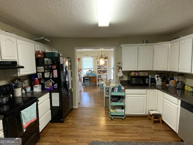 kitchen with decorative light fixtures, wood-type flooring, white cabinets, black appliances, and a textured ceiling