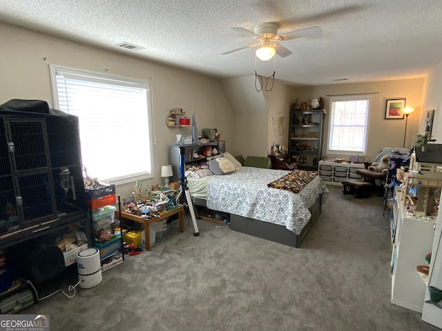 carpeted bedroom featuring ceiling fan and a textured ceiling