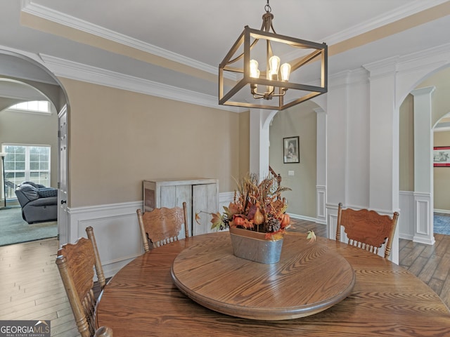 dining area featuring a raised ceiling, crown molding, hardwood / wood-style floors, and a notable chandelier