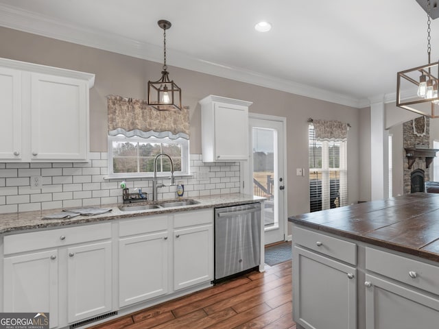 kitchen with pendant lighting, sink, crown molding, white cabinetry, and stainless steel dishwasher