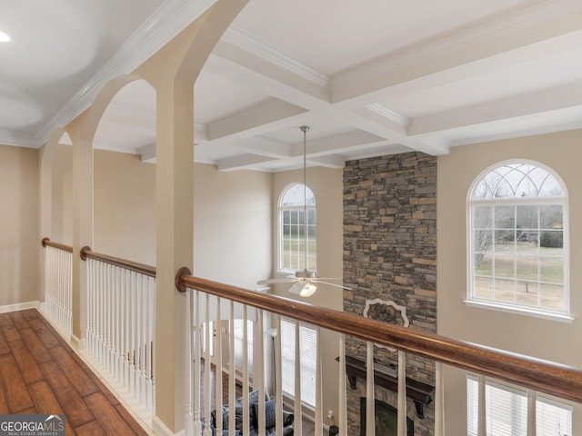 corridor with coffered ceiling, beamed ceiling, dark hardwood / wood-style floors, and a healthy amount of sunlight