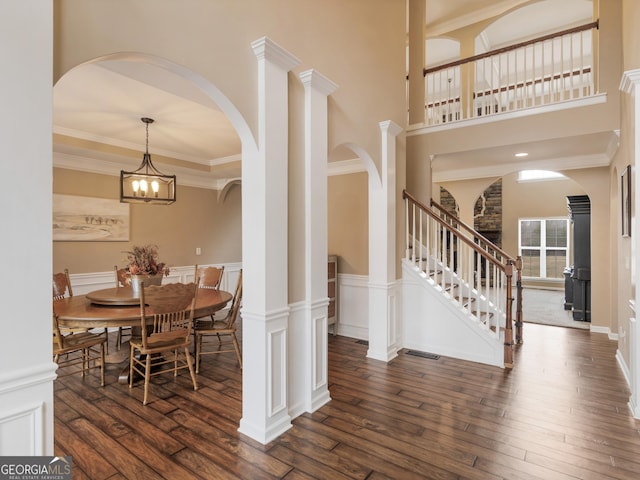 dining area featuring dark hardwood / wood-style flooring, ornamental molding, a chandelier, and a high ceiling