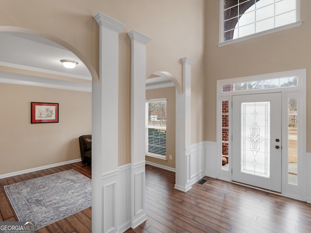 foyer featuring ornamental molding, a towering ceiling, and hardwood / wood-style floors