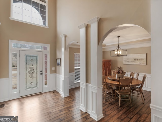 foyer entrance featuring dark wood-type flooring, crown molding, and an inviting chandelier