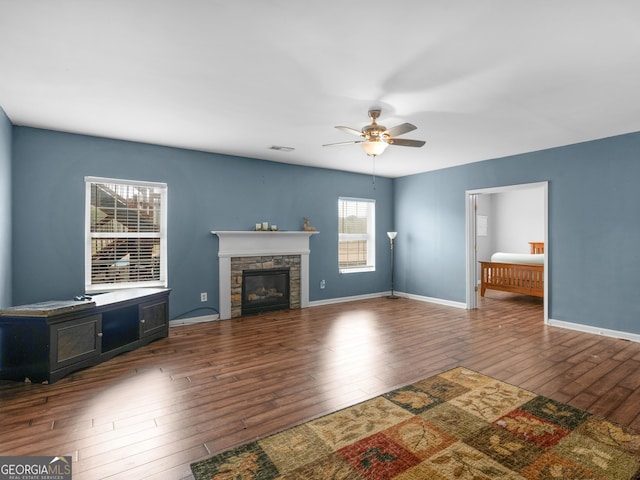 unfurnished living room with ceiling fan, a fireplace, and dark hardwood / wood-style flooring