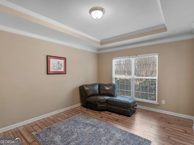 sitting room with ornamental molding, a tray ceiling, and hardwood / wood-style floors