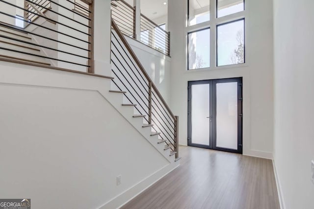 entrance foyer with a towering ceiling, french doors, and hardwood / wood-style flooring