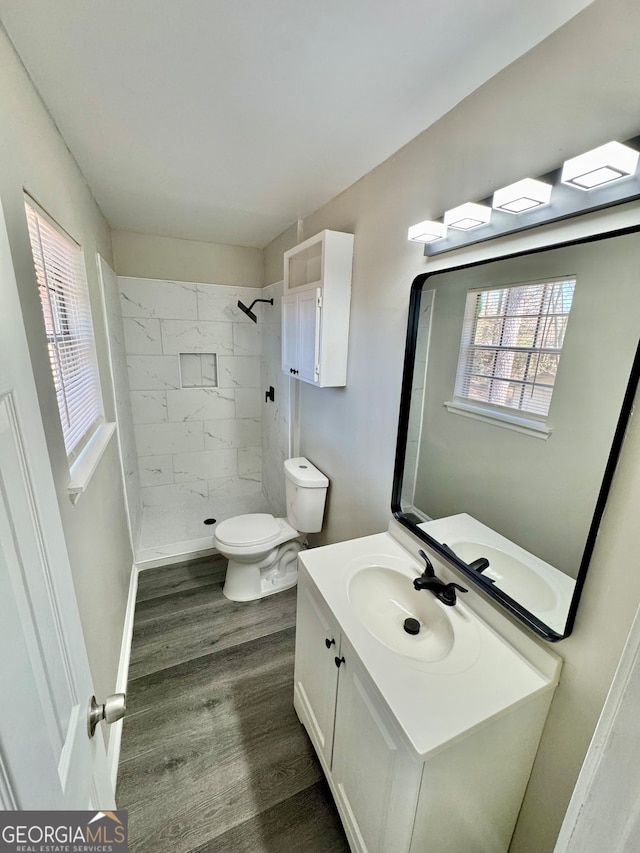 bathroom featuring toilet, a stall shower, wood finished floors, and vanity